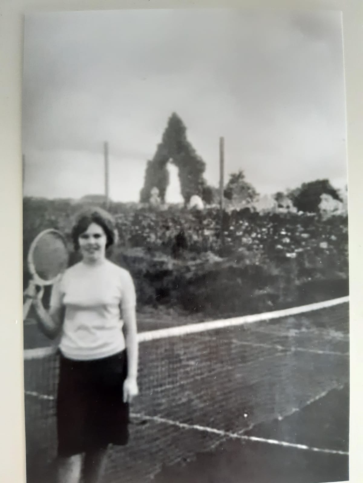 A member at the net with the ruined abbey arch in the background